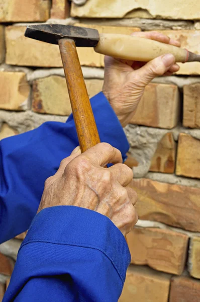 Elderly hands with a hammer and chisel.