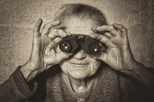 Mulher idosa olha através de binóculos . — Fotografia de Stock