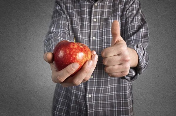 Persona sosteniendo sabrosa manzana roja y mostrando el pulgar hacia arriba . — Foto de Stock