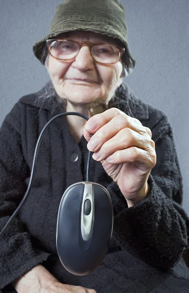 Oudere vrouw bedrijf in een computermuis — Stockfoto