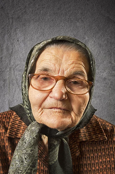 Portrait of an old woman on a vintage background. — Stock Photo, Image