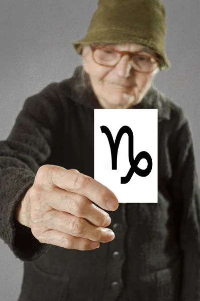 인쇄 된 별자리 염소 자리 로그인 카드를 들고 노인 여성 — 스톡 사진