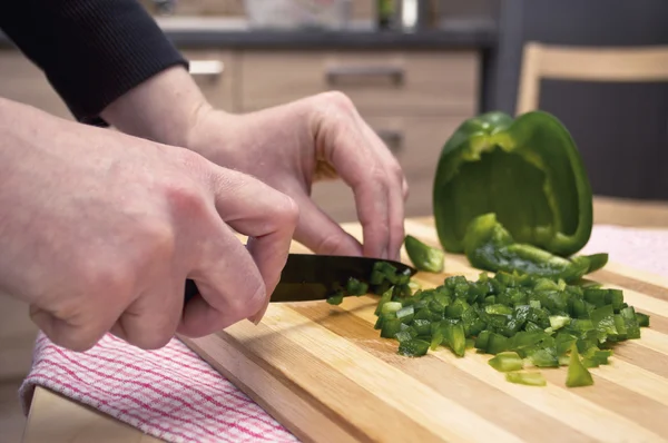 Kvinna hand skära en grön paprika i köket. — Stockfoto