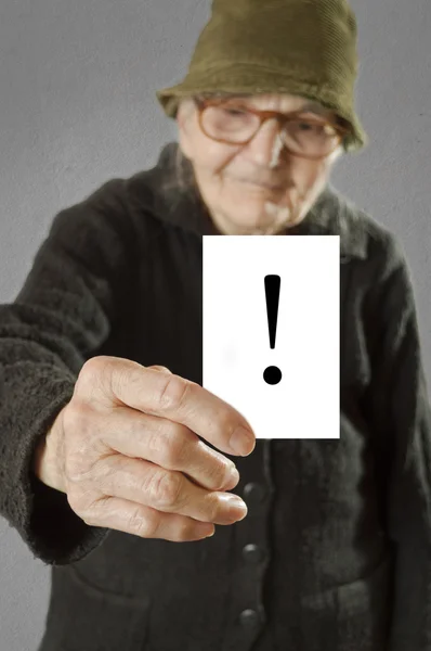 Elderly woman holding card with printed exclamation mark — Stock Photo, Image