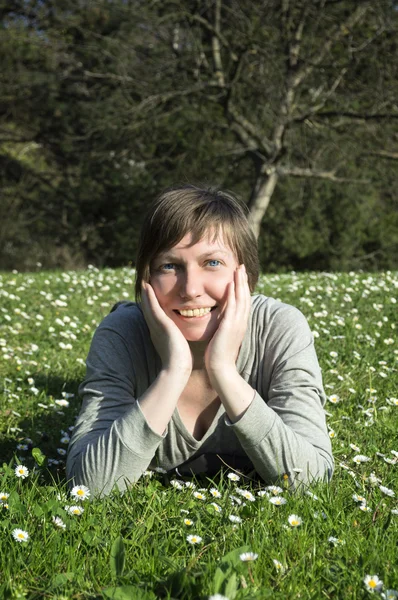 Piękna młoda kobieta znajduje się na zielonej trawie. — Zdjęcie stockowe