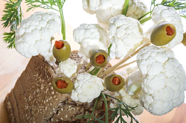 Un ramo de aceitunas y coliflor en una cesta de pan — Foto de Stock