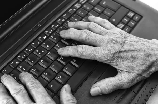 Elderly hands on keyboard of laptop. — Stock Photo, Image