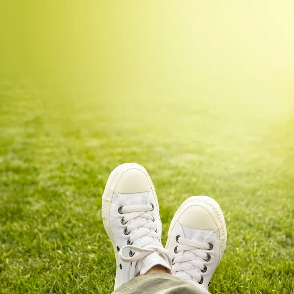 Un paio di scarpe da ginnastica bianche nell'erba sotto il sole — Foto Stock