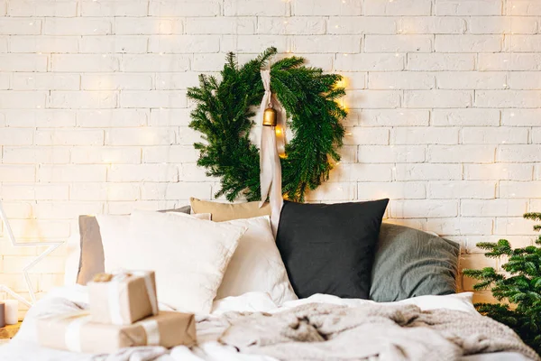 멋지네요, 크리스마스 침실 인테리어 디자인을 겨울 휴가 철에 초대합니다. 큰 침대 옆에는 크리스마스 트리가 있고 뒤에는 따뜻 한 불빛이 비추는 큰 화환 이 있다. — 스톡 사진