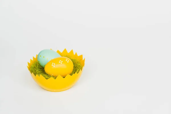 Sárga és kék húsvéti tojás tojáshéj kosárban, fehér alapon elkülönítve. Húsvéti ünnepek és ünnepségek. — Stock Fotó