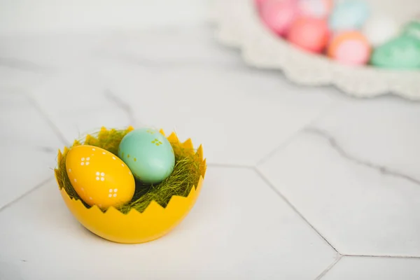 卵の殻のバスケットに黄色と青のイースターエッグ。イースター休暇とお祝い. — ストック写真