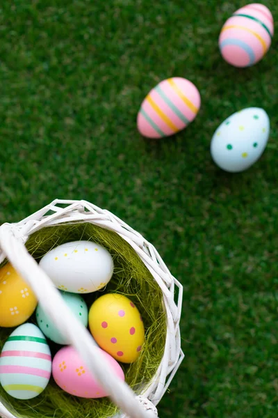 カラフルな黄色、ピンク、織りバスケットや緑の芝生の中で青イースターの卵と垂直イースターの背景。コピースペース付きのトップビュー。イースター休暇｜ソーシャルメディアの背景. — ストック写真