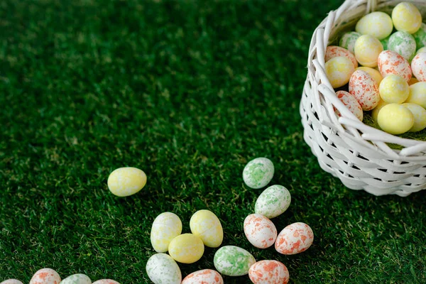 カラフルな黄色、ピンク、織りバスケットや緑の芝生の中で青イースターの卵とイースターの背景。コピースペース付きのトップビュー。イースターの祝日のバナーとヘッダー. — ストック写真