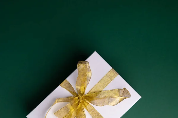 Christmas gift box, present with golden ribbon. Top view of Christmas gift on green background. Merry Christmas. Winter holidays, New Year, birthday presents. Seasons greetings copy space for text