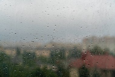 Bulutlu bir sonbahar gününde pencere camında yağmur damlaları