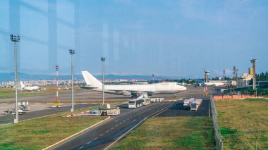 Güneşli bir sabahta havaalanı penceresinden uçağın pistte durduğu yere bakın.