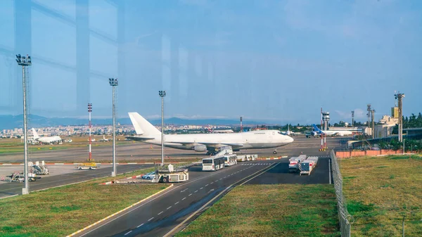 Güneşli bir sabahta havaalanı penceresinden uçağın pistte durduğu yere bakın.