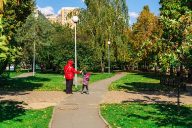 Büyükanne ve torun iki yolun kesiştiği yerde güneşli bir sonbahar gününde hava kabarcıklarıyla oynuyorlar.