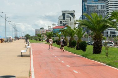 Turistler setin tepesinde dinleniyor ve arka planda bulutlu bir gökyüzünün altında palmiye ağaçları var.