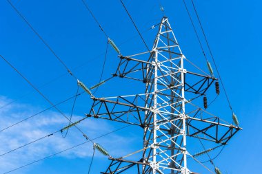 Güneşli bir günde mavi gökyüzüne karşı elektrik iletim hatlarının metal direği