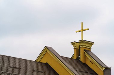 Hristiyan haçı, bulutlu bir gökyüzünün arka planında kilisenin çatısında