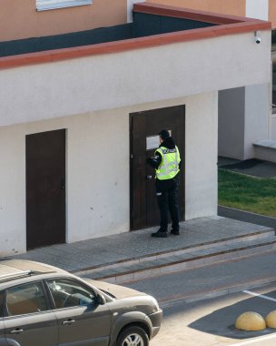 Mesleki görevlerini yerine getirirken bir apartmanın girişinde üniformalı Ukraynalı bir polis. Formdaki yazı: 