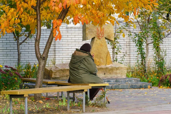 Eine Alte Frau Betet Auf Einer Bank Unter Einem Herbstbaum — Stockfoto