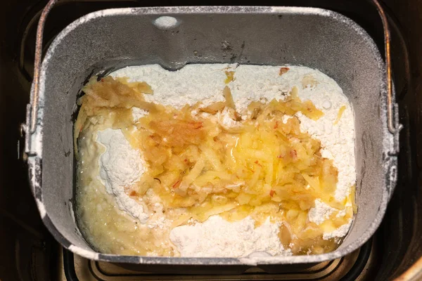 Mashed apple in a batch of homemade bread in a metal bowl of a bread machine