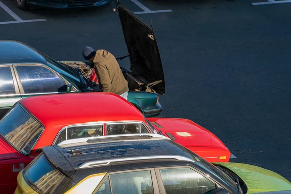 運転手は自分の車を修理しようとしている 一列には 太陽の光の中の駐車場の多色車 車の窓の家の反射です — ストック写真