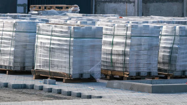 Doğal ışık ve yol çalışması altındaki bir şehirde yol kiremitleri döşemek için bir inşaat sahasında paketlerdeki yol kiremitleri blokları