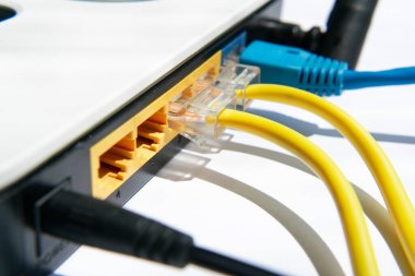 Close-up of a light-keyed router on a white background with an antenna fragment and two-color data cables. Internet access for home and office
