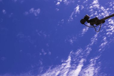 Satellite dish converters aim at a large blue space of a bright blue sky with white cirrus clouds
