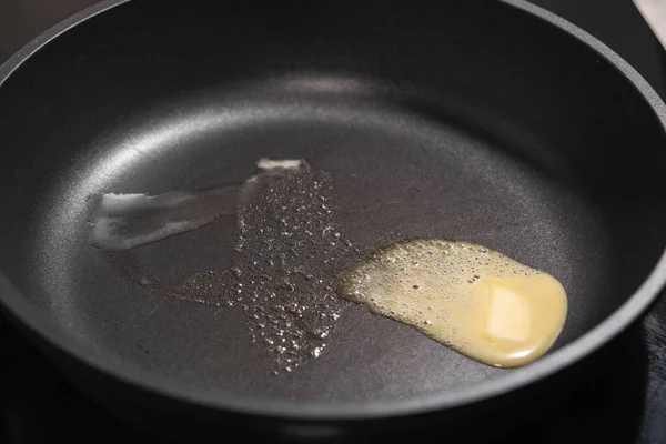 Tereyağı, metal bir tavanın sıcak yapışmaz yüzeyinde eriyor.