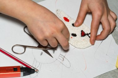 Kızın elinde 3D yazdırma kalemiyle yaptığı Paskalya Tavşanı heykelciği var. Yanında da 3 boyutlu kırmızı bir kalem, bir kalem ve bir makas var. Üst görünüm