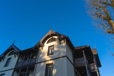 Akşam güneşinin ışınları mavi gökyüzüne karşı ahşap bir evin aydınlık duvarında. Alt kenar görünümü