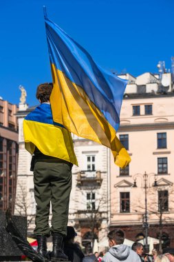 Ukrayna bayrağı, bir Avrupa şehrinde güneşli bir günde Rusya 'nın Ukrayna' yı işgaline karşı protestocuların mitinginde bir eylemcinin elinde.