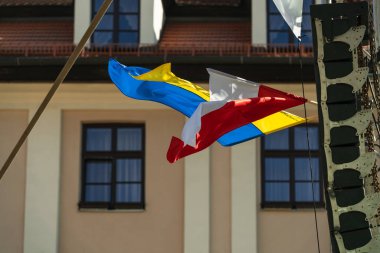 Ukrayna ve Polonya 'nın bayrakları, güneşli bir günde arka planda pencere ve duvarlara karşı güçlü bir rüzgarla gelişir. Polonya 'nın Ukrayna ile Rusya ile savaşta dayanışması