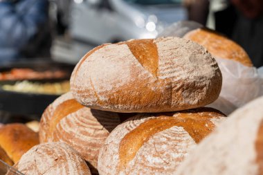 Taze pişmiş yuvarlak ekmek ve güneş ışığı altında bir sokak pazarının tezgahında altın bir kabuk. Köy ekmeğiyle Polonya pastanesi.