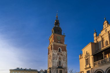 Eski Krakow 'un tarihi merkezi gün batımında, taş kuledeki saat akşam güneşinin ışınları altında.