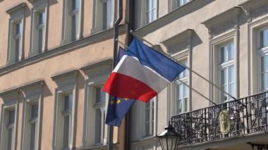 Güneşli bir günde Polonya 'nın Krakow kentindeki Fransız Konsolosluğu' nun eski duvarında Fransız ve Avrupa Birliği bayrakları dalgalanıyor