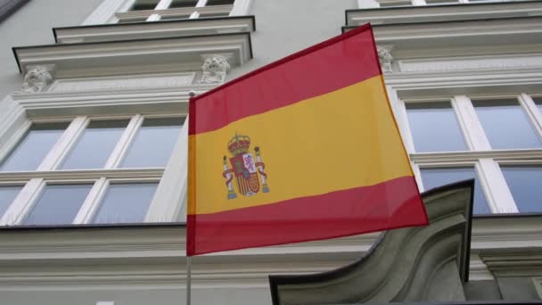 A spanyol zászló egy régi épület falán lóg, és a szélben repked a kék ég felé.