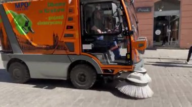 Krakow, Malopolska, Polonya - Mart 2022: Güneşli bir günde bir belediye yolu ve kaldırım temizleme aracı Old Krakow caddesi boyunca sürüyor