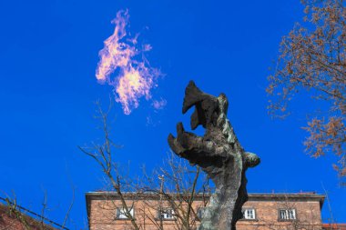 Wawel ejderhası, güneşli bir günde şatonun kırmızı tuğla duvarına ateş püskürtür.
