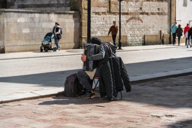 Ukraynalı bir mülteci, güneşli bir günde Eski Krakow Kasabası 'nın caddesinde yoldan geçenler arasında akordeon çalıyor.