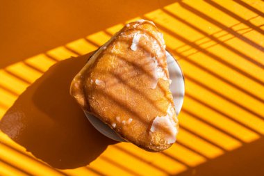 Geleneksel Polonya turtası, turuncu bir yüzeyde beyaz şekerli, güneş ışığı şeritli.