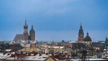 Şehrin orta çağ pazar meydanında St. Mary Bazilikası ve belediye binası kulesiyle Eski Krakow 'un hava manzarası bulutlu havalarda Krakow evlerinin çatılarında kar.