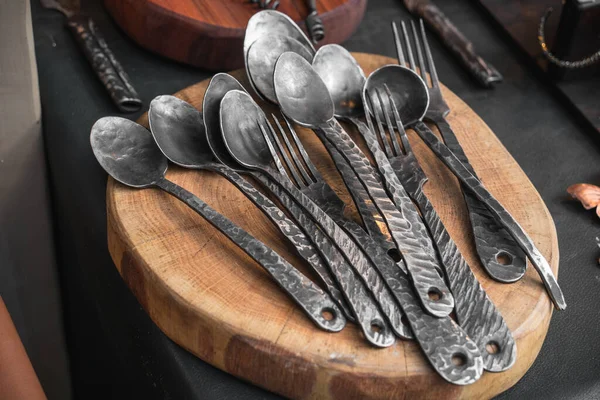 Metal spoons and handmade forks wrought by blacksmith at the fair, medieval utensils in modern times