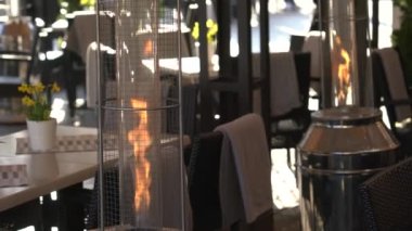 Açık hava lokantası, güneş ışığı ve COVID-19 'dan sonra şehir kafesindeki masalarda yanan gaz tüpleri.