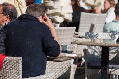 Polonya, Krakow, Ana Pazar Meydanı, 12 Nisan 2022: Yaz kafe masaları, Eski Krakow 'un merkezindeki St. Mary Bazilikası yakınlarındaki taş döşeli meydanda yürüyen turistler.