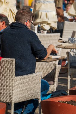 Polonya, Krakow, Ana Pazar Meydanı, 12 Nisan 2022: Yaz kafe masaları, Eski Krakow 'un merkezindeki St. Mary Bazilikası yakınlarındaki taş döşeli meydanda yürüyen turistler.